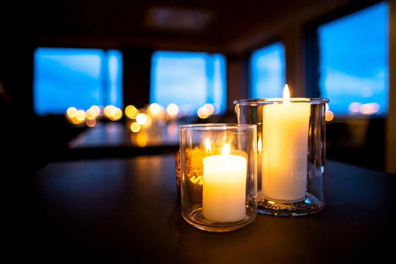 Candles in glass holders with a blurred background of more candles and soft light.