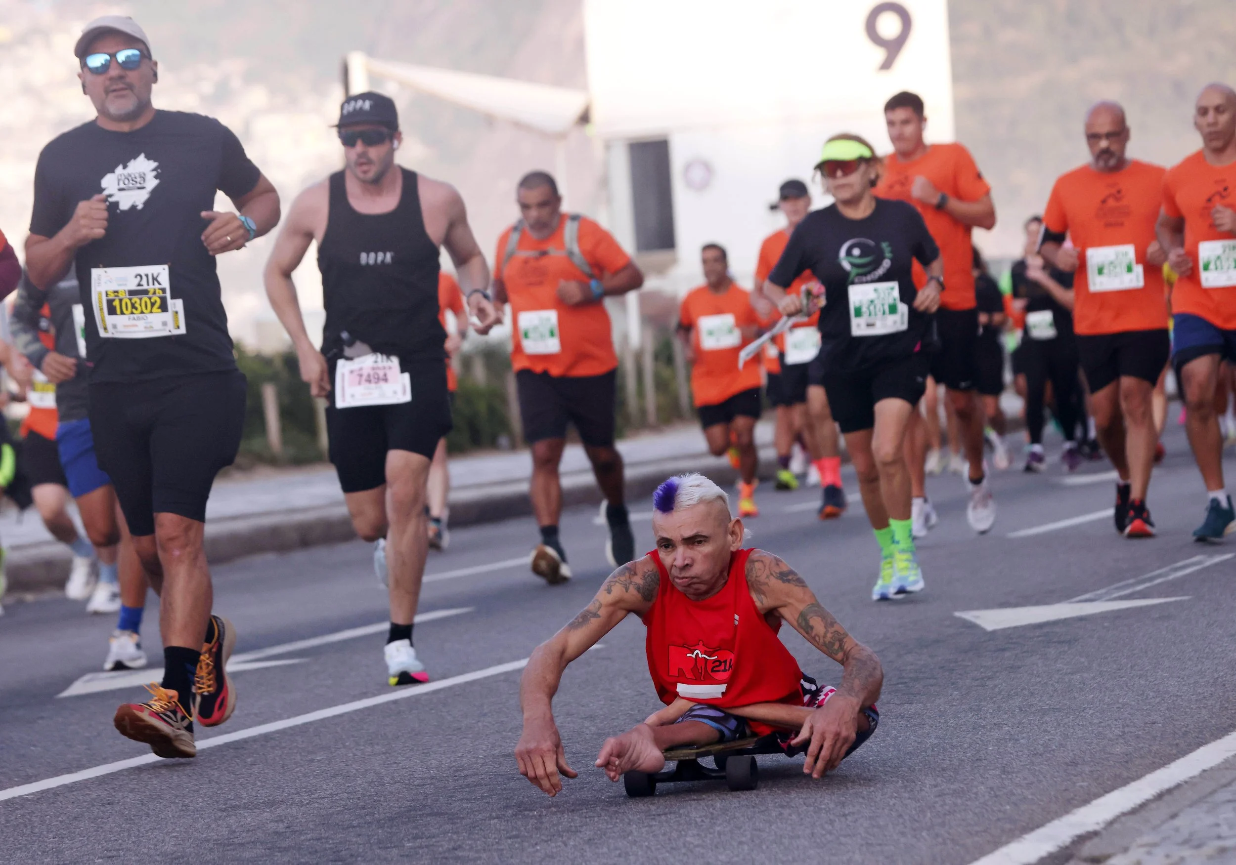 A para-athlete propels himself forward on a skateboard alongside thousands of runners during the 27th Rio de Janeiro International Half Marathon.