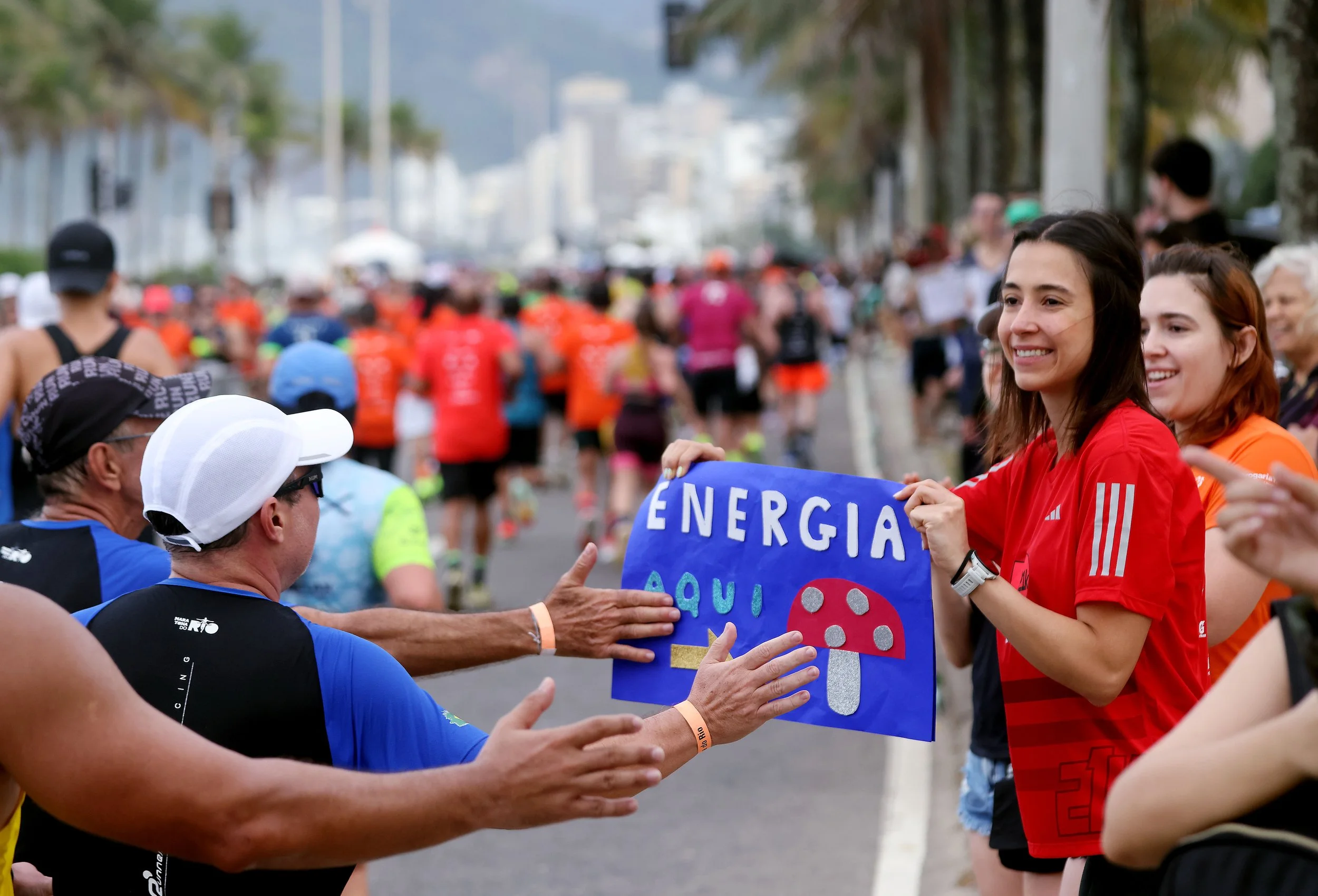 Runners touch a sign saying ‘Energy Here’ as they pass through Ipanema during the 2025 Rio de Janeiro Marathon on Sunday, June 22. With a course that showcases Rio’s stunning coastline