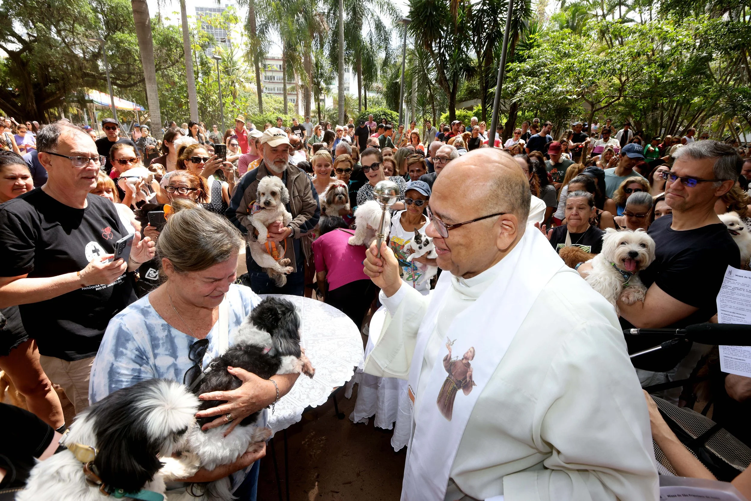 PADRE JORGE blessed over 100 pet owners who gathered at Praça Nossa Senhora da Paz in Ipanema, spreading prayers and holy water for the Blessing of the Animals