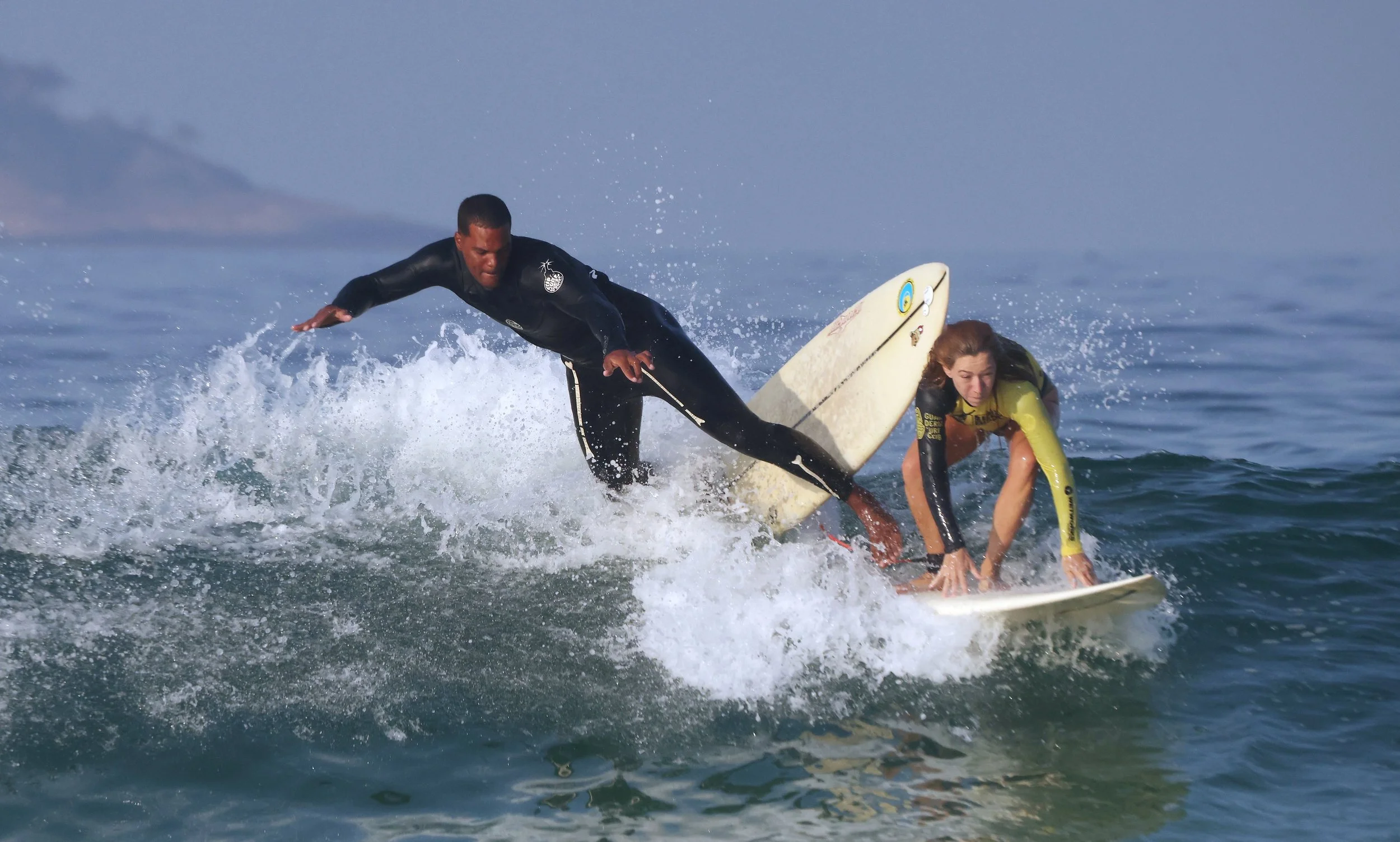 Tight takeoff at Arpoador! Two surfers scramble for position on a small but snappy morning wave—one driving down the line, the other mid-air in a dramatic drop.
