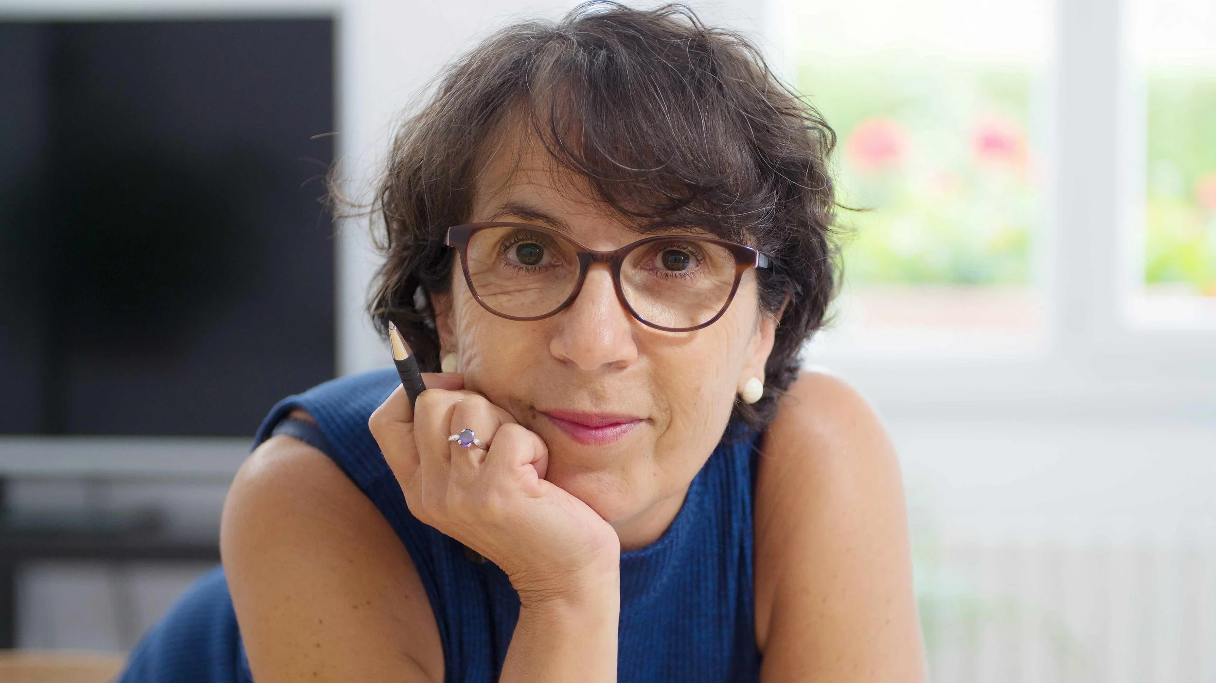 a-middle-aged-woman-with-glasses-holding-a-pencil-and-resting-her-head-on-her-hand-16x9.jpg