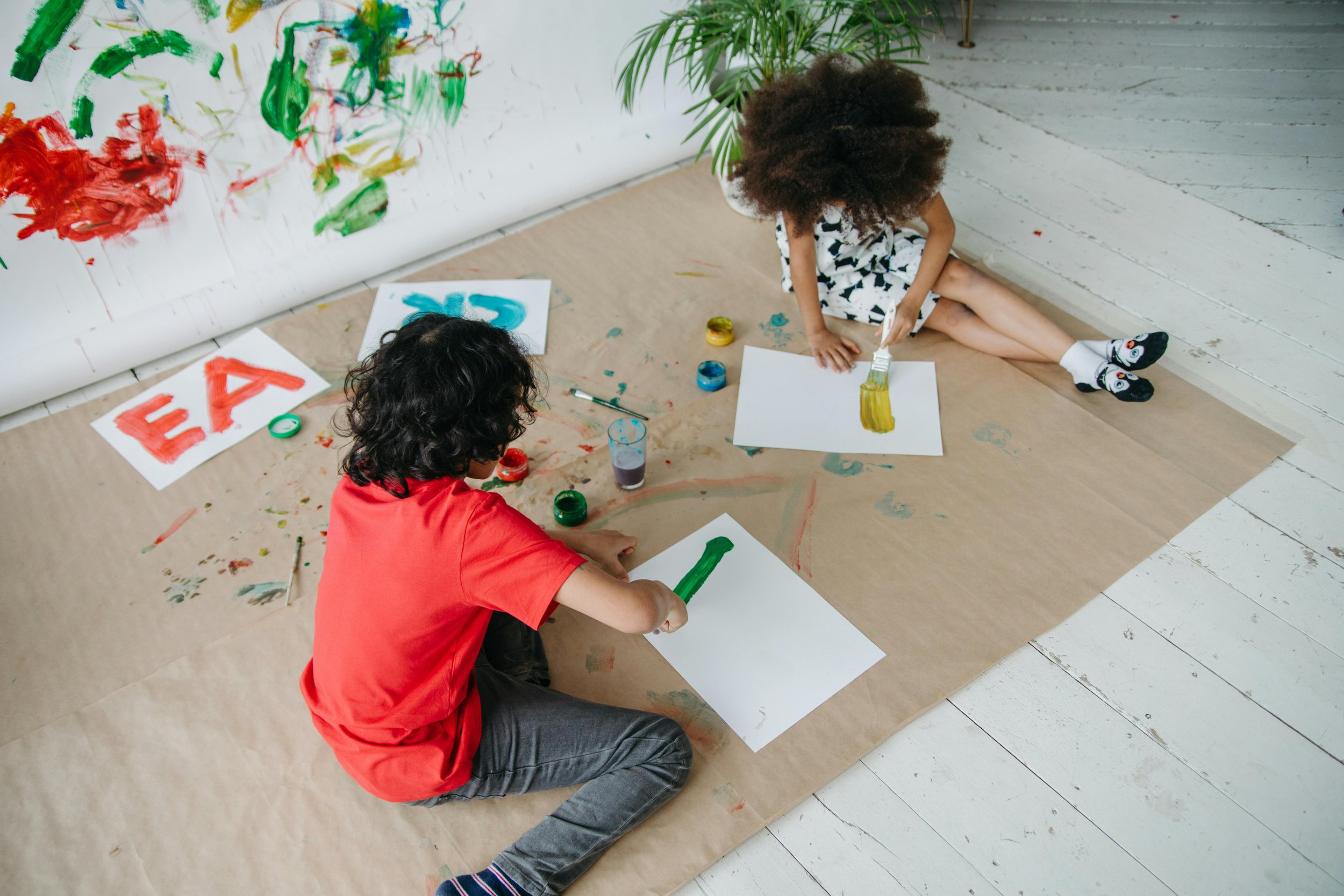 Two children painting on the floor during a creative play activity that supports emotional expression, imagination, and mindful learning.