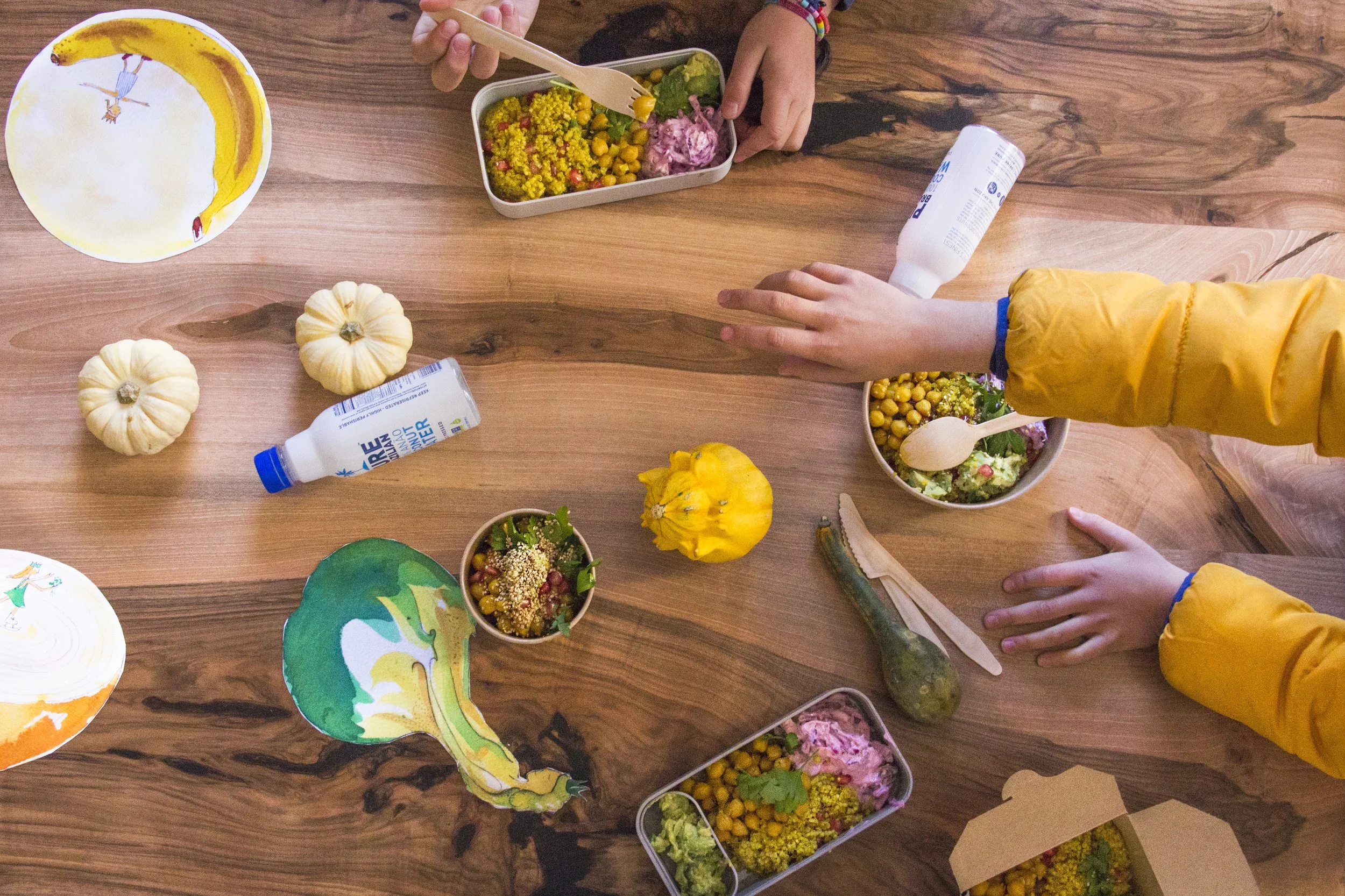 Children sharing colourful plant-based meals at a wooden table, encouraging positive mealtimes and adventurous eating.