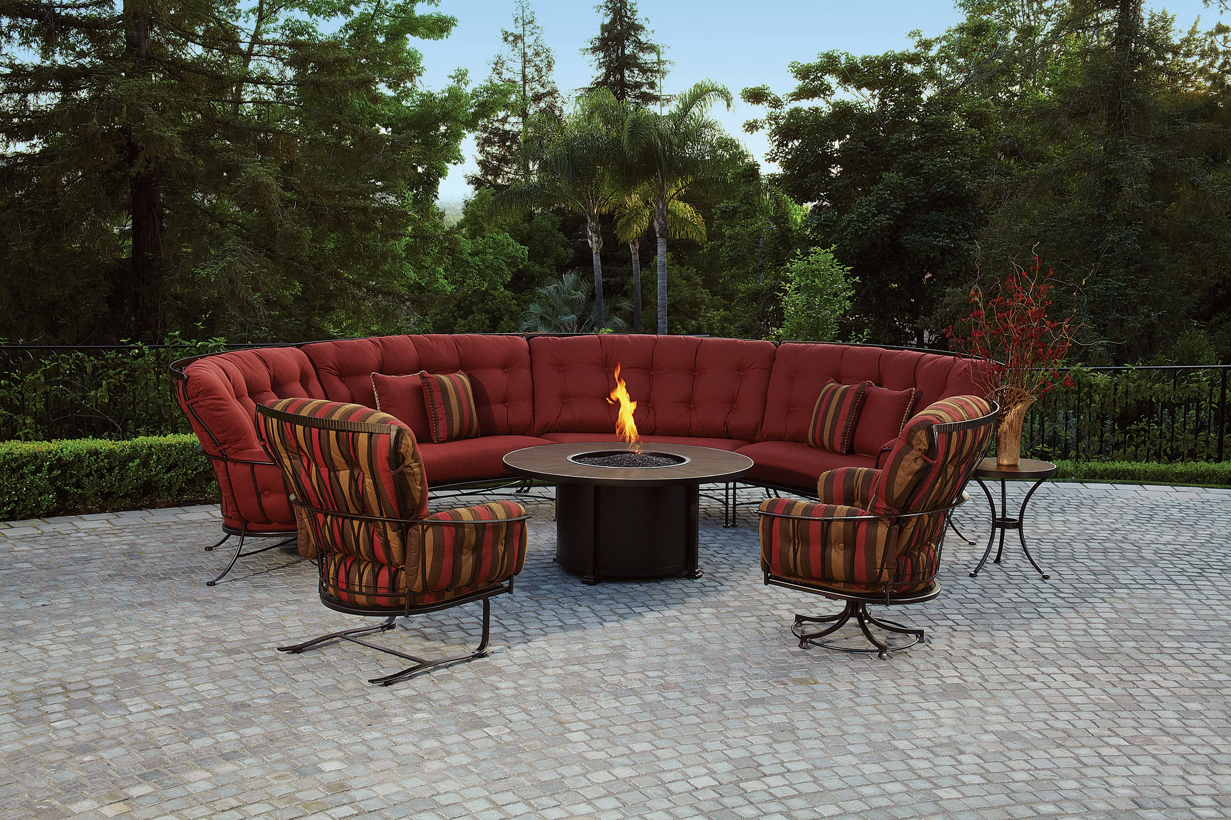 Monterra Sectional with frames made of powder coated wrought iron with swivel rocker lounge chair and spring rocker lounger chair. OW LEE Firepit has 54” porcelain top with wrought iron base and slide out tray for easy propane tank refill.