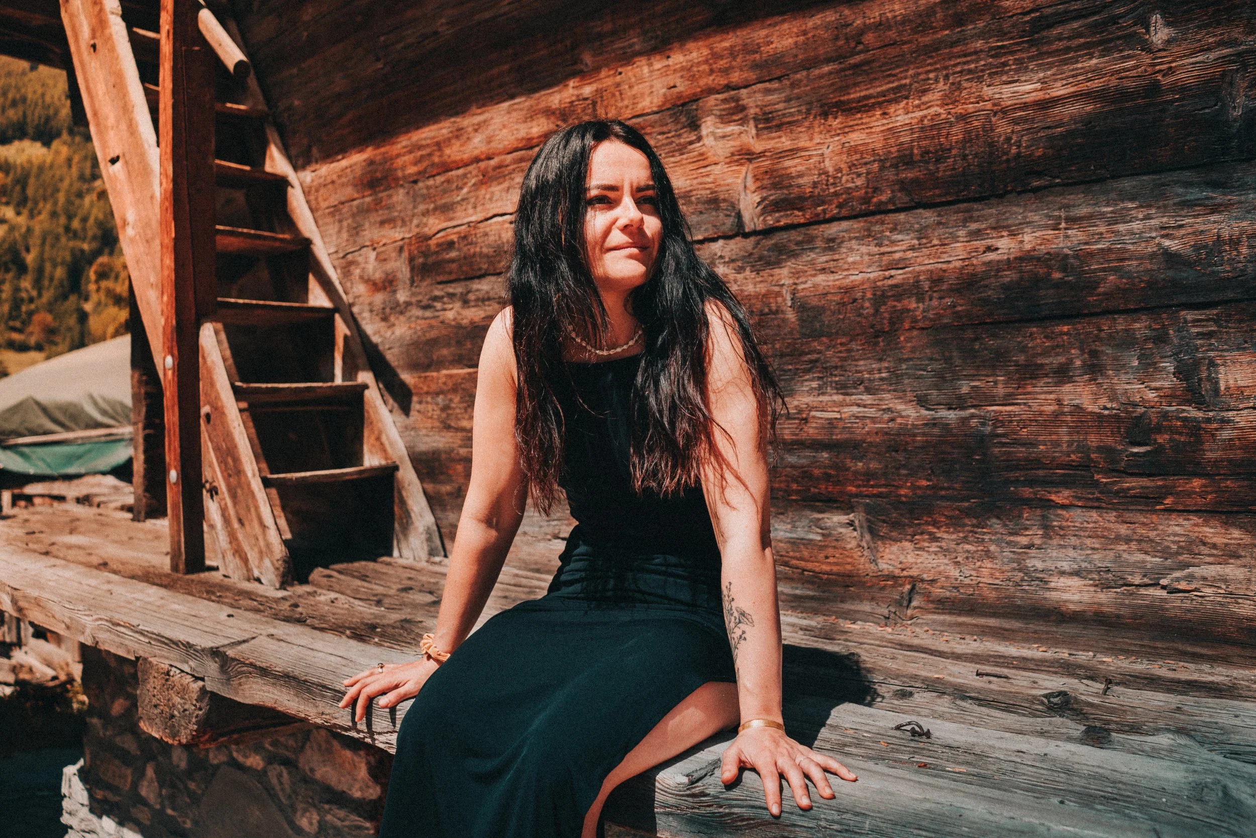 Portrait of a woman in Evolène, surrounded by traditional wooden chalets in the Swiss Alps.