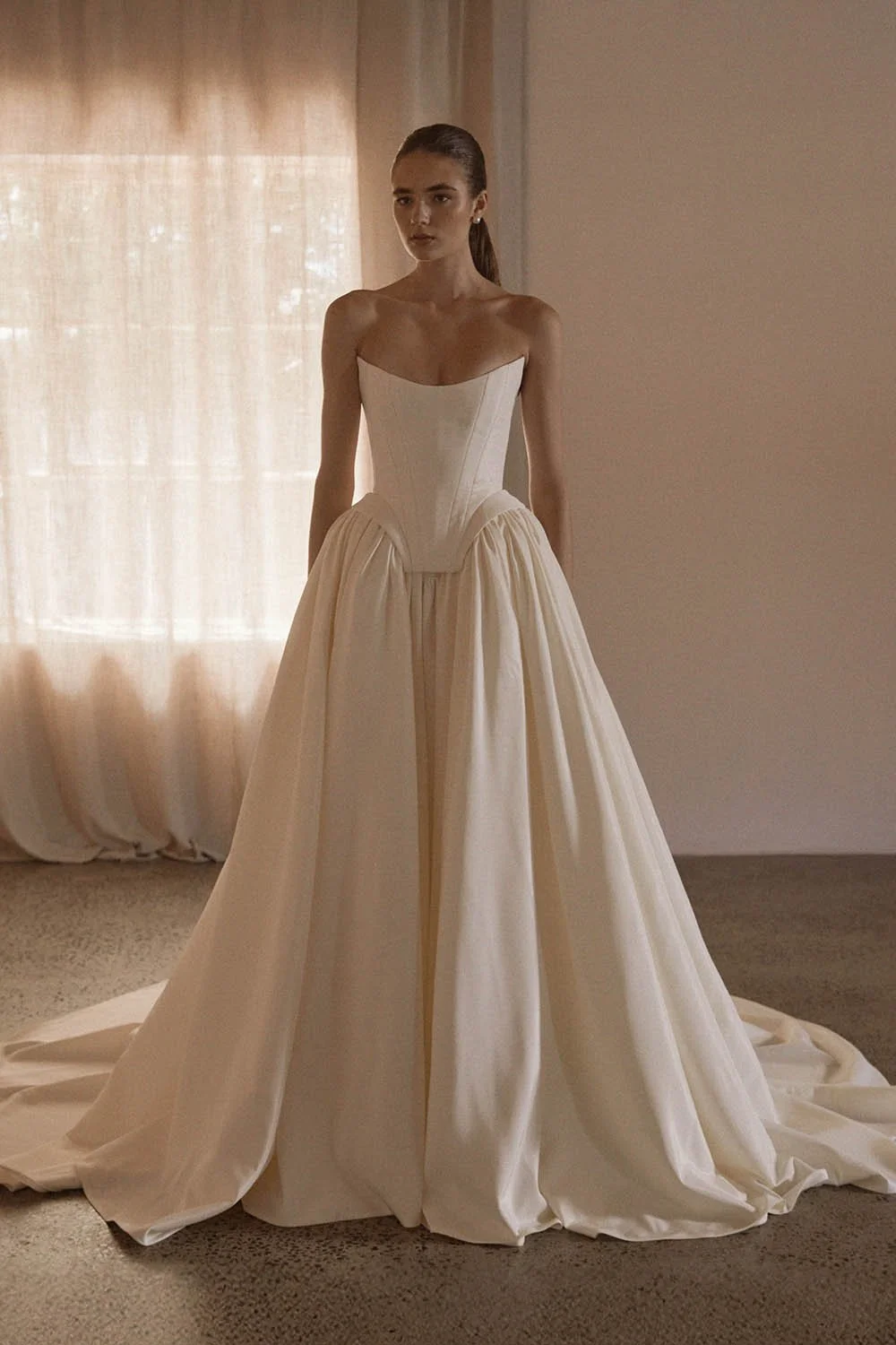 Louis Corset by Vagabond Bridal, exclusively available at The Art of Bridal, Brisbane bridal boutique. Silk-inspired ivory taffeta ensemble featuring a sculpted boned corset with a statement square basque and a striking scoop neckline, exuding old-wo