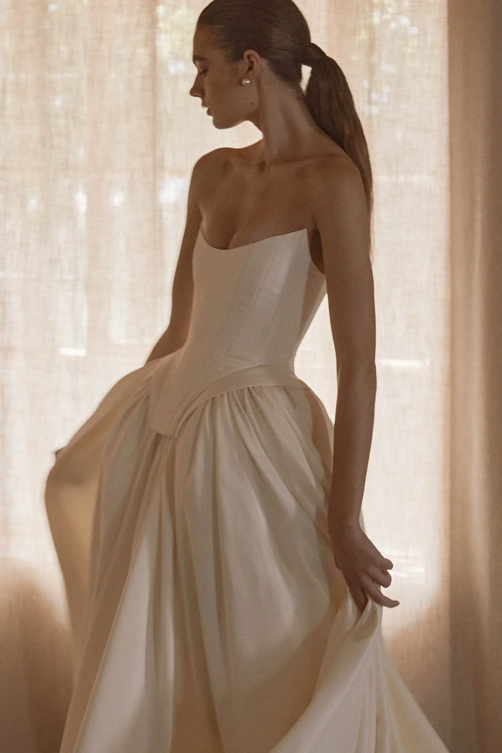 Louis Corset by Vagabond Bridal, exclusively available at The Art of Bridal, Brisbane bridal boutique. Silk-inspired ivory taffeta ensemble featuring a sculpted boned corset with a statement square basque and a striking scoop neckline, exuding old-wo