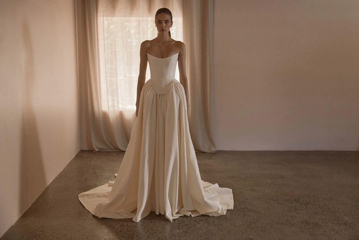 Louis Corset by Vagabond Bridal, exclusively available at The Art of Bridal, Brisbane bridal boutique. Silk-inspired ivory taffeta ensemble featuring a sculpted boned corset with a statement square basque and a striking scoop neckline, exuding old-wo