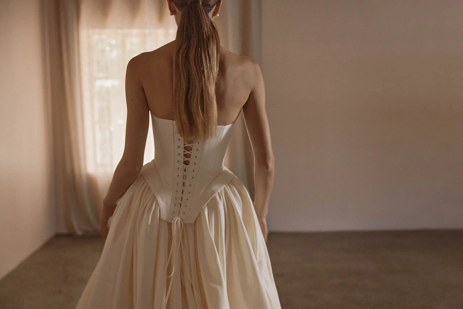 Louis Corset by Vagabond Bridal, exclusively available at The Art of Bridal, Brisbane bridal boutique. Silk-inspired ivory taffeta ensemble featuring a sculpted boned corset with a statement square basque and a striking scoop neckline, exuding old-wo