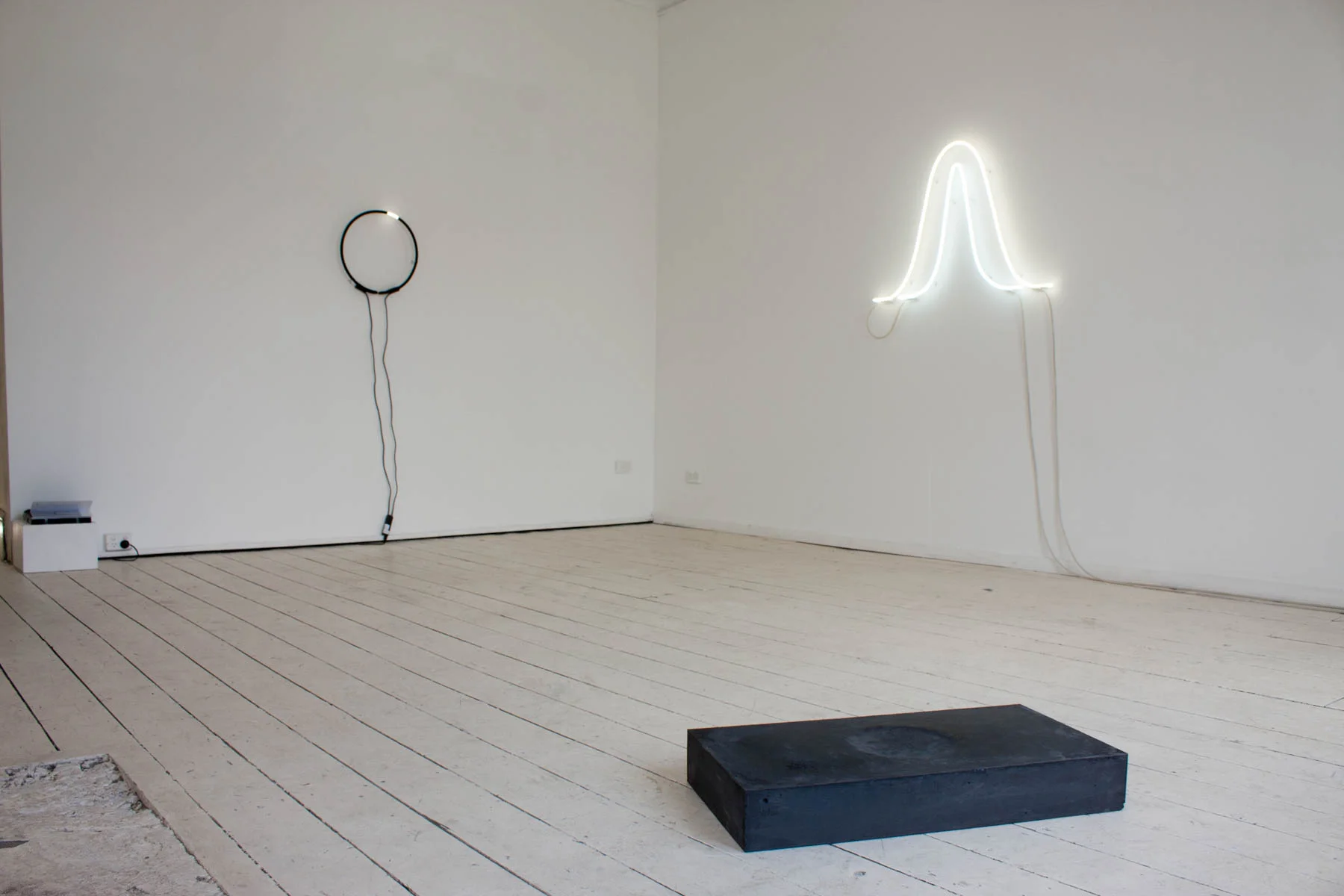 (left to right) 'white white (summer and winter solstice)', 2017, neon light, electrical components, 70 x 100cm; 'Hora Somni: for Vera Rubin', 2017, cast black concrete with Papaver Somniferum seeds, 10 x 35 x 70cm / Installation view in 'Steady Illiterate Movement', Seventh Gallery, Melbourne