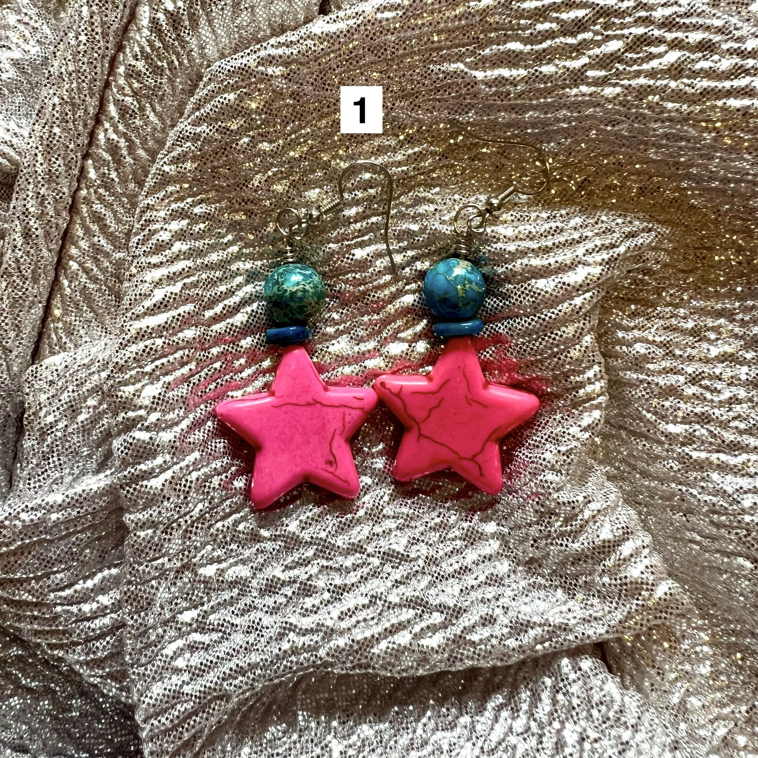 Beaded earrings with a pink star stone bead, topped with a blue crystal laying on a silver backdrop
