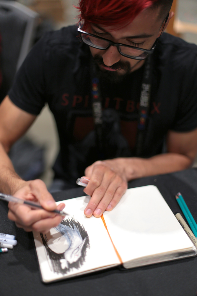 Cody Jimenez sketching at the Mexicanx Initiative art booth during Worldcon 76 (Photo by Dianita Cerón)