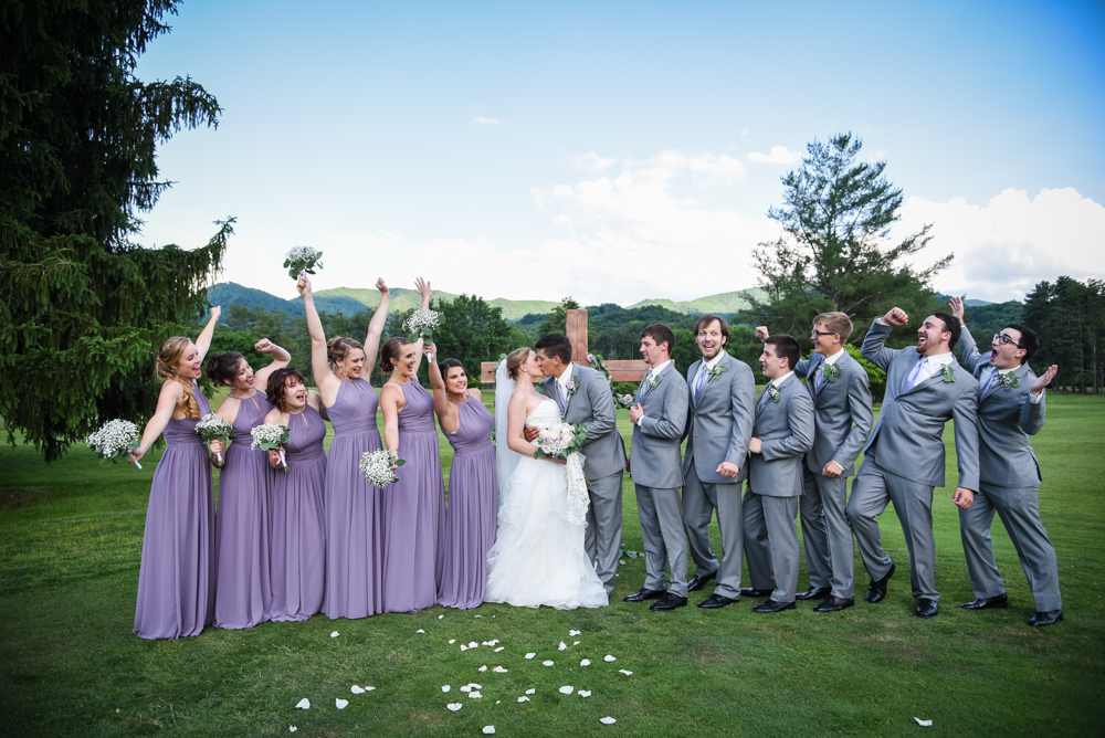 bridal party cheering while bride and groom kiss