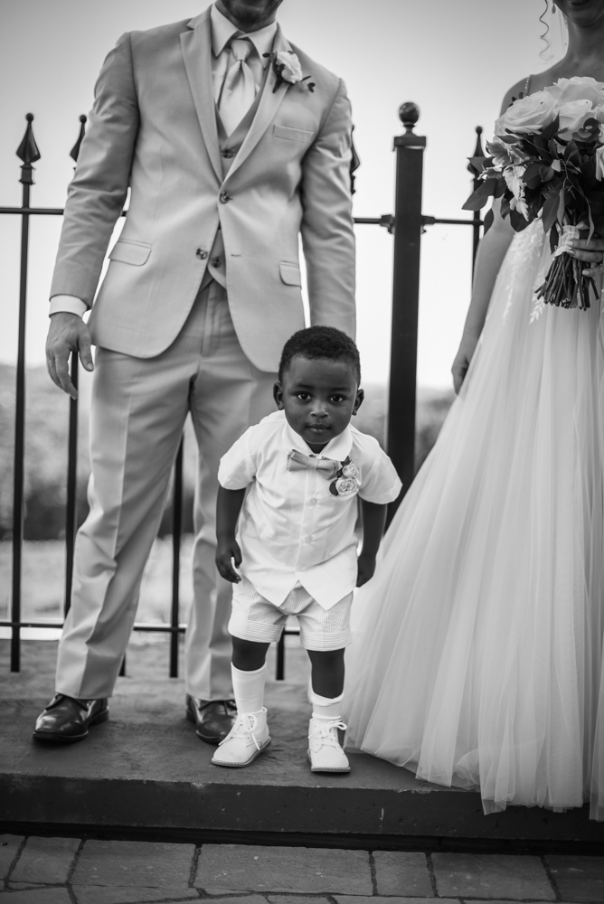 Ring bearer looking at camera while standing at the feet of the bride and groom