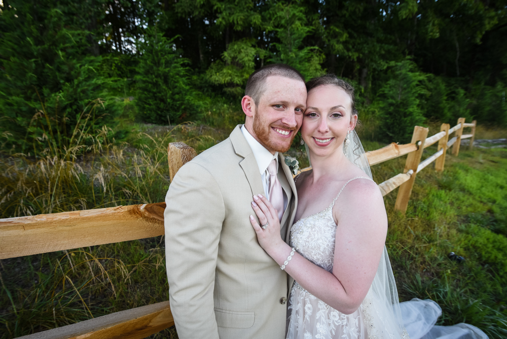 bride and groom standing in front of a fence and trees