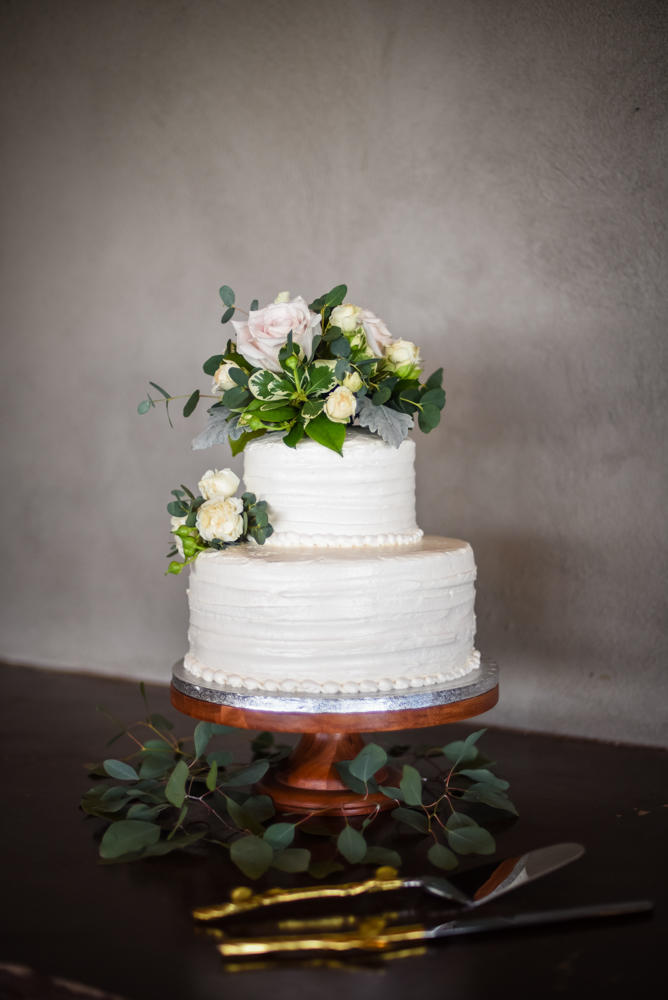 two tier white wedding cake with pink and cream flowers and greenery on top from Publix