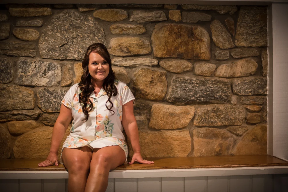 bride before her wedding sitting in front of a rock wall smiling