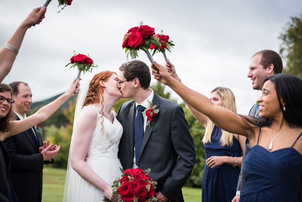Bride and groom kiss under flower bouquets