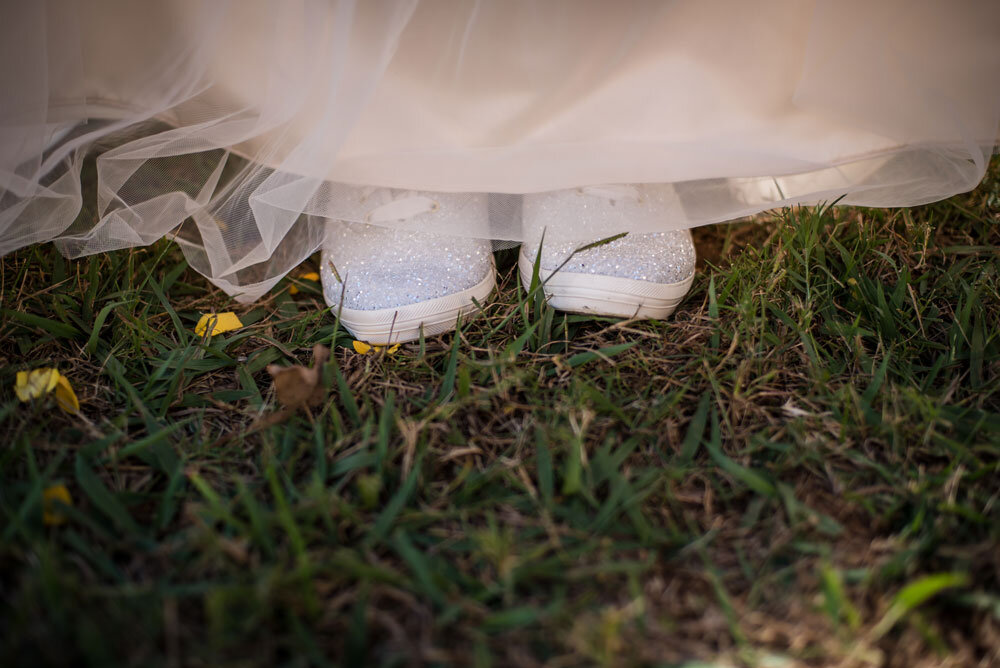 Brides glittery shoes peeping out from the bottom of her wedding gown