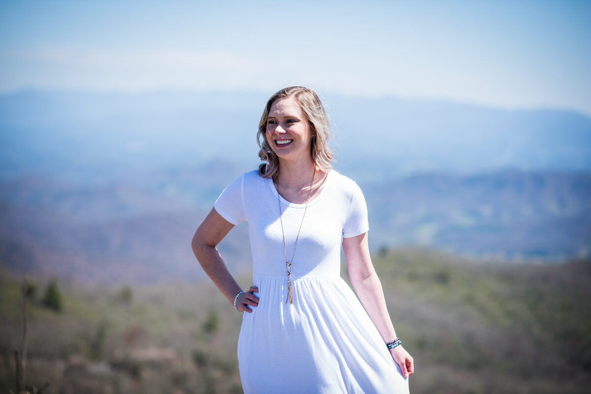 Bride smiling in white wedding dress at mountaintop elopement