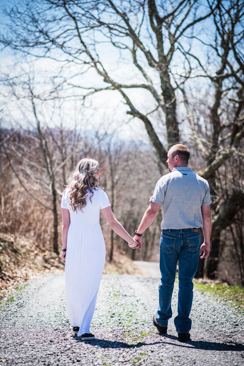 Bride and groom walking and holding hands on a gravel road at mountaintop elopement