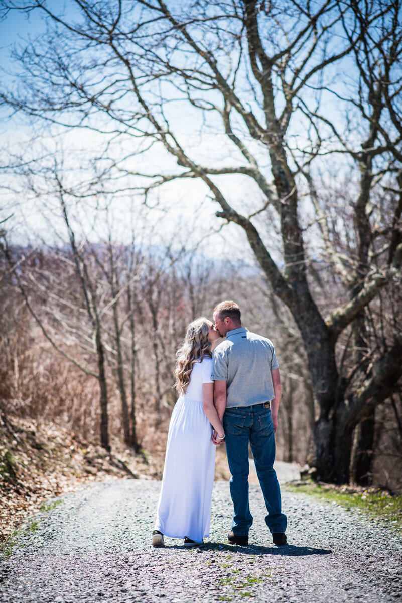 Bride and groom kiss outside on gravel road at mountaintop elopement