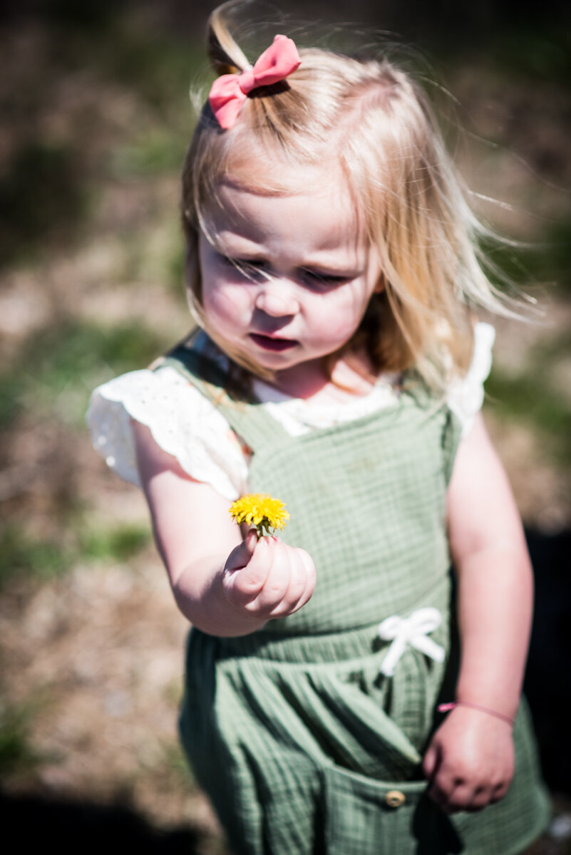 Young girl holding and looking at a flower