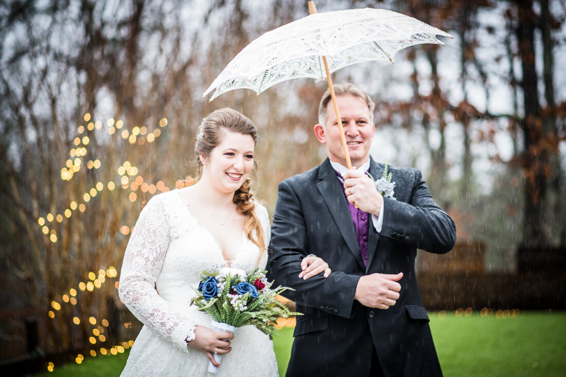 Bride walking down the aisle with father under white umbrella
