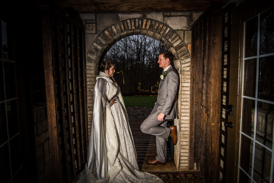 Bride and groom standing in a castle archway facing each other