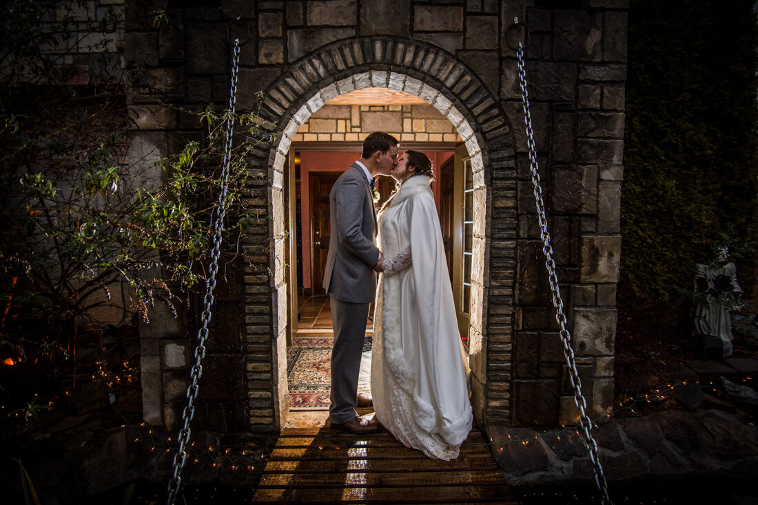 Bride and groom kissing in castle archway