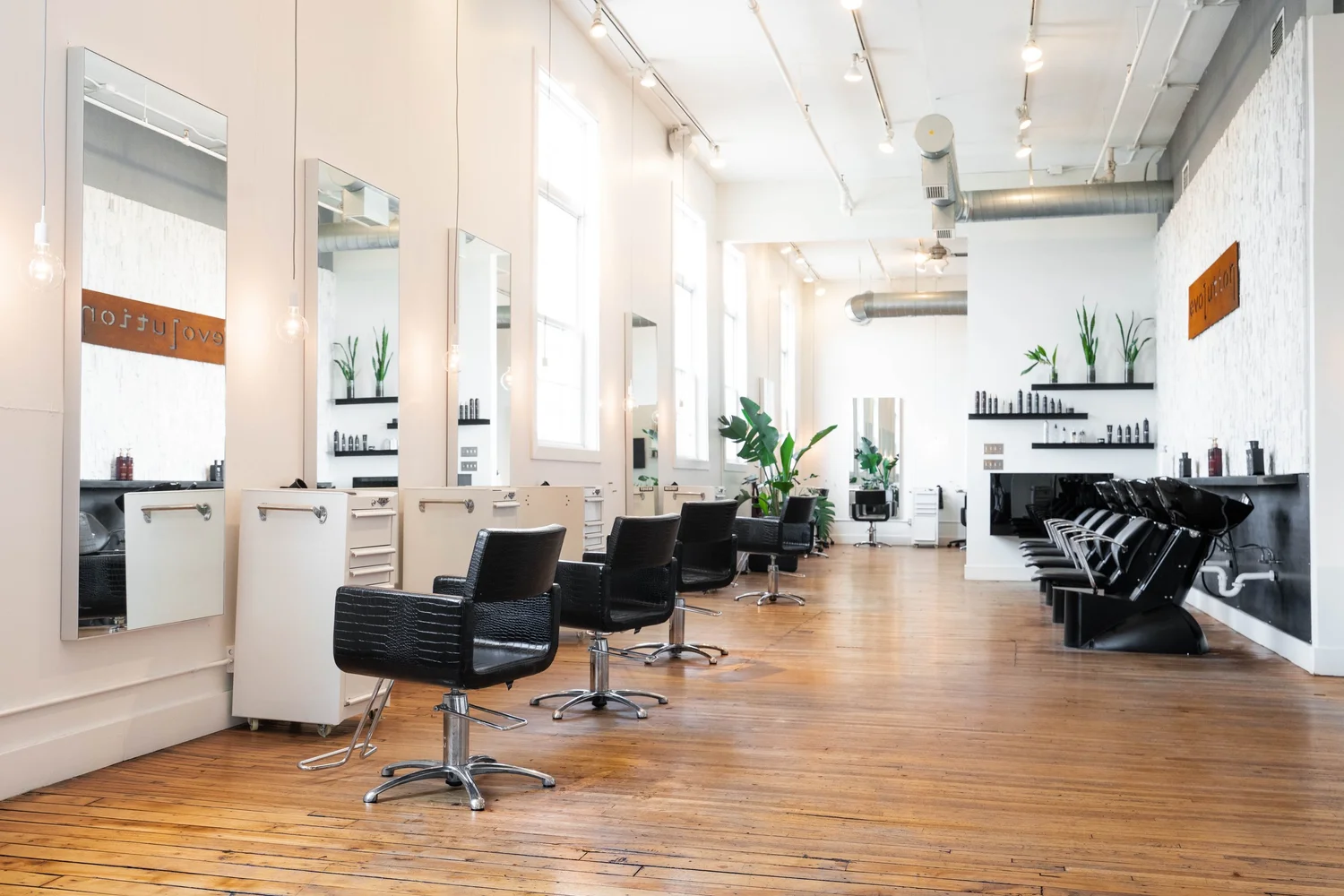 Salon floor with styling chairs and shampoo bowls