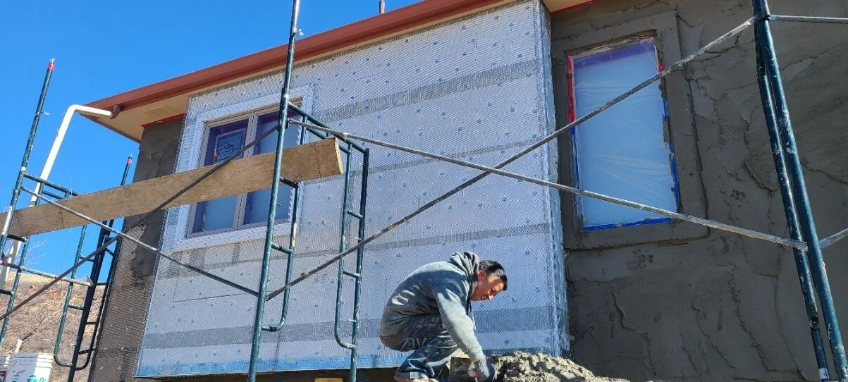 Construction worker applying stucco to house exterior with scaffolding in place