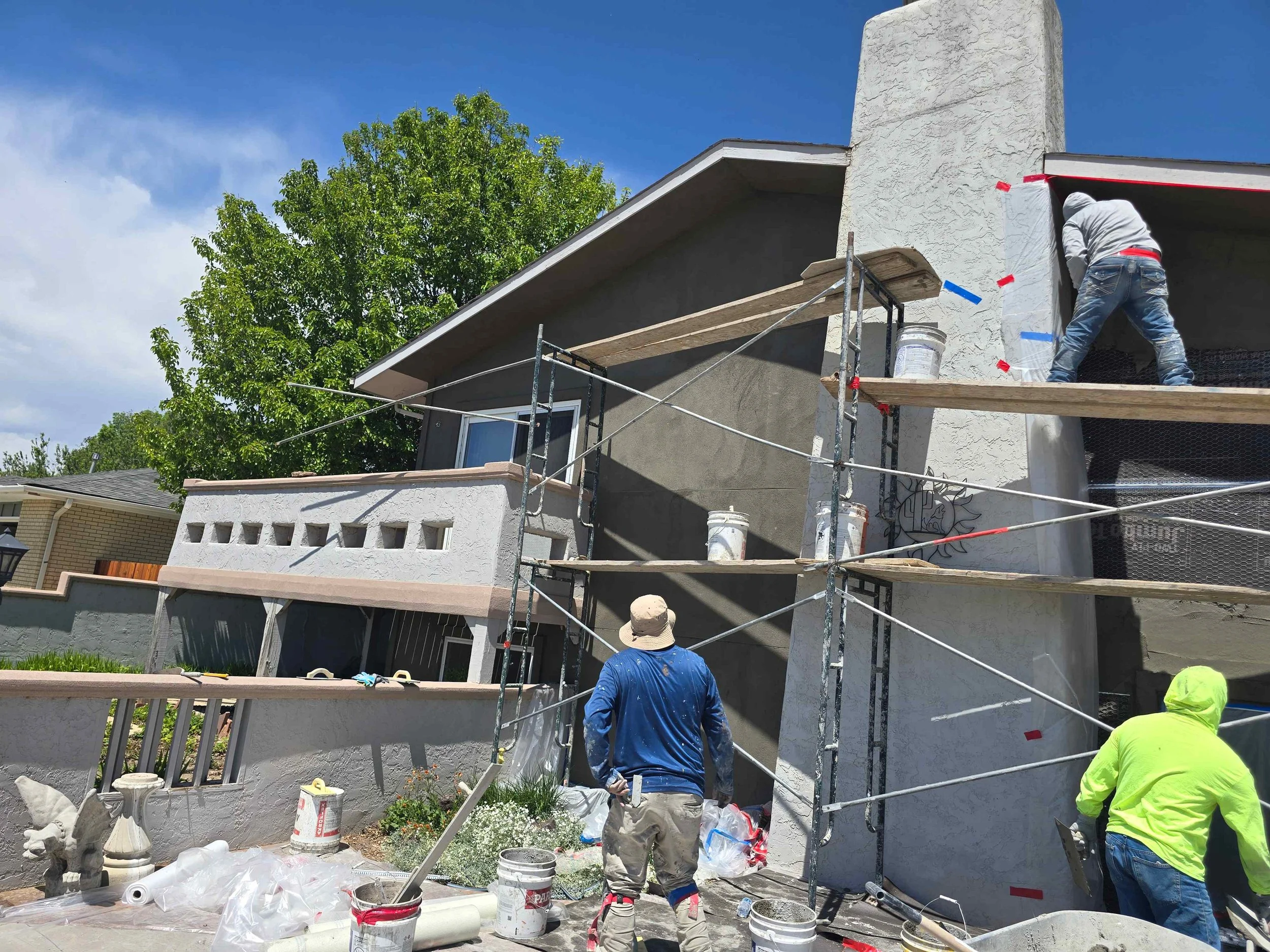 Before stucco installation showing exposed wall framing, weather barrier, metal lath and scaffolding on a home exterior.