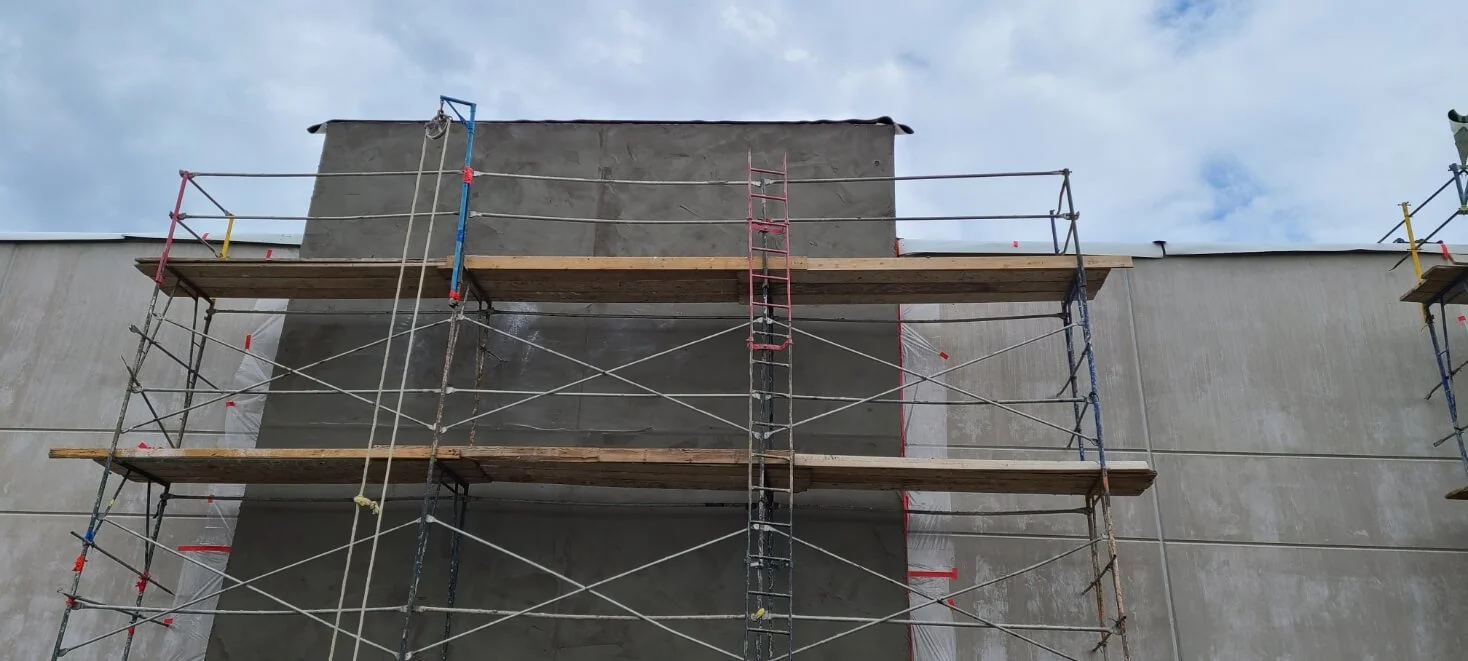 Construction Commercial Stucco Firestone scaffolding against a concrete wall.