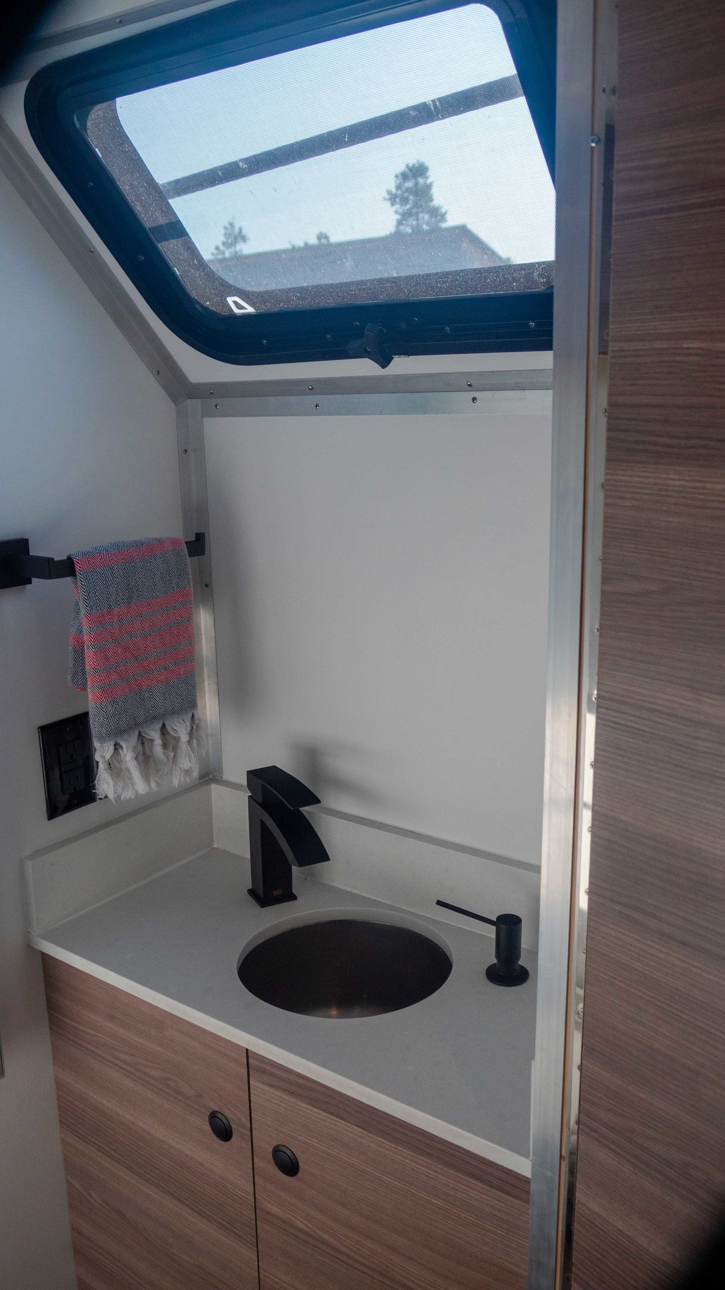 wash room with matte black finishes, stainless steel sink, and window