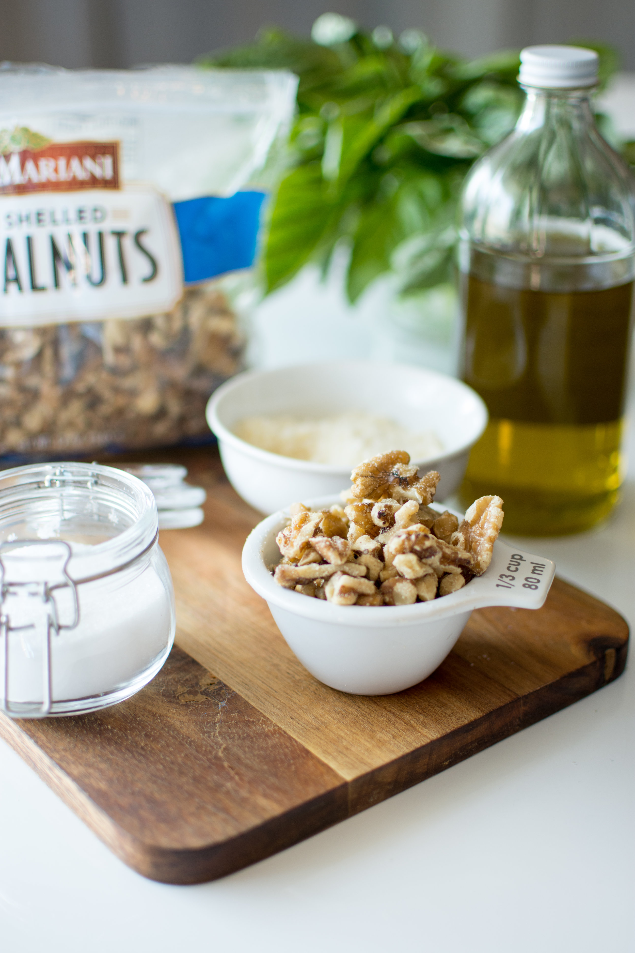 Start by collecting all of your ingredients in one place - fresh basil leaves, Mariani walnuts, garlic, salt and good olive oil. You can use a pre grated parmesan cheese or a block of fresh parmesan. In the next photo, I’ll show you a super easy way to grate a whole block of cheese in just a few seconds.
