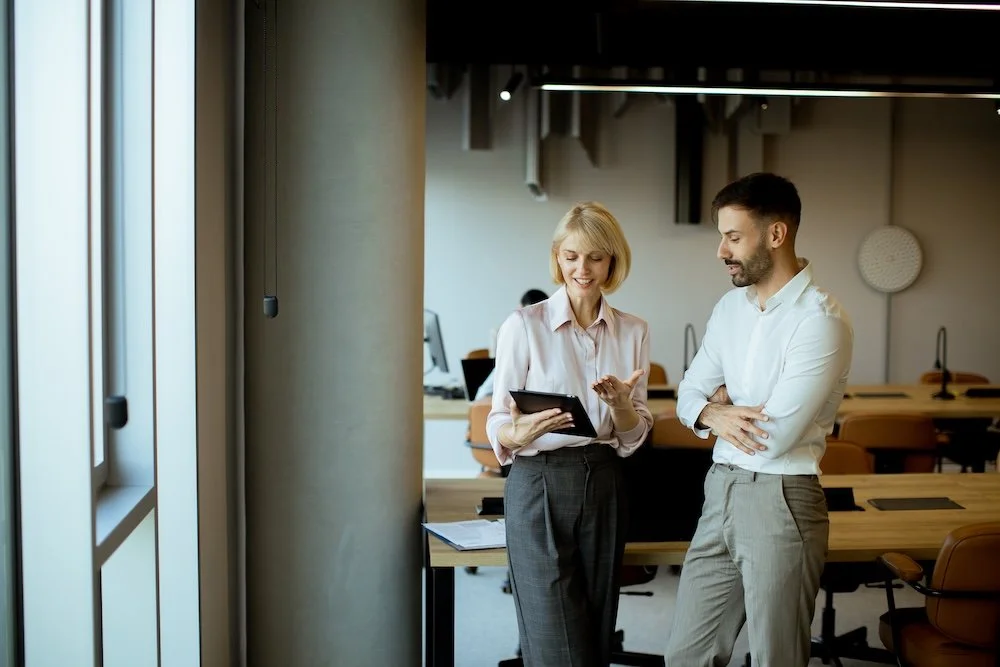 Two professionals reviewing a tablet in a modern office space for rent with natural light and collaborative workspace