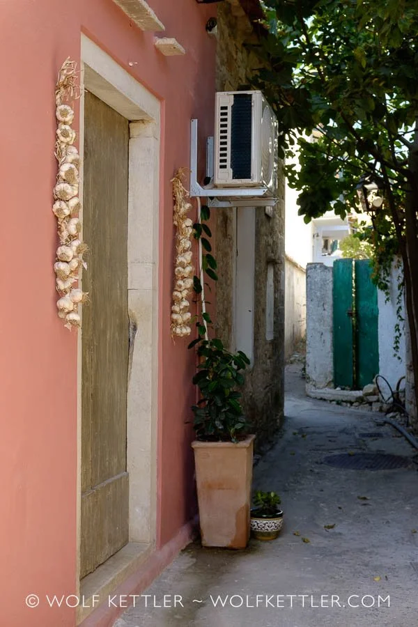 Garlic hung up in strings on the wall of a house in Mediterranean Greece, framing the front door.