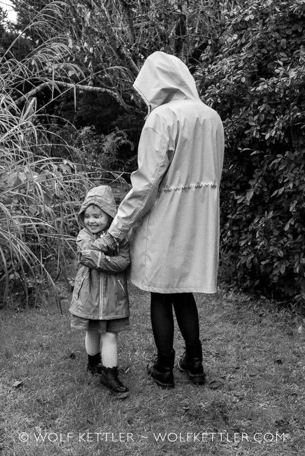 A mother and child portrait by photographer Wolf Kettler in his secluded garden on an atmospheric, rainy day.