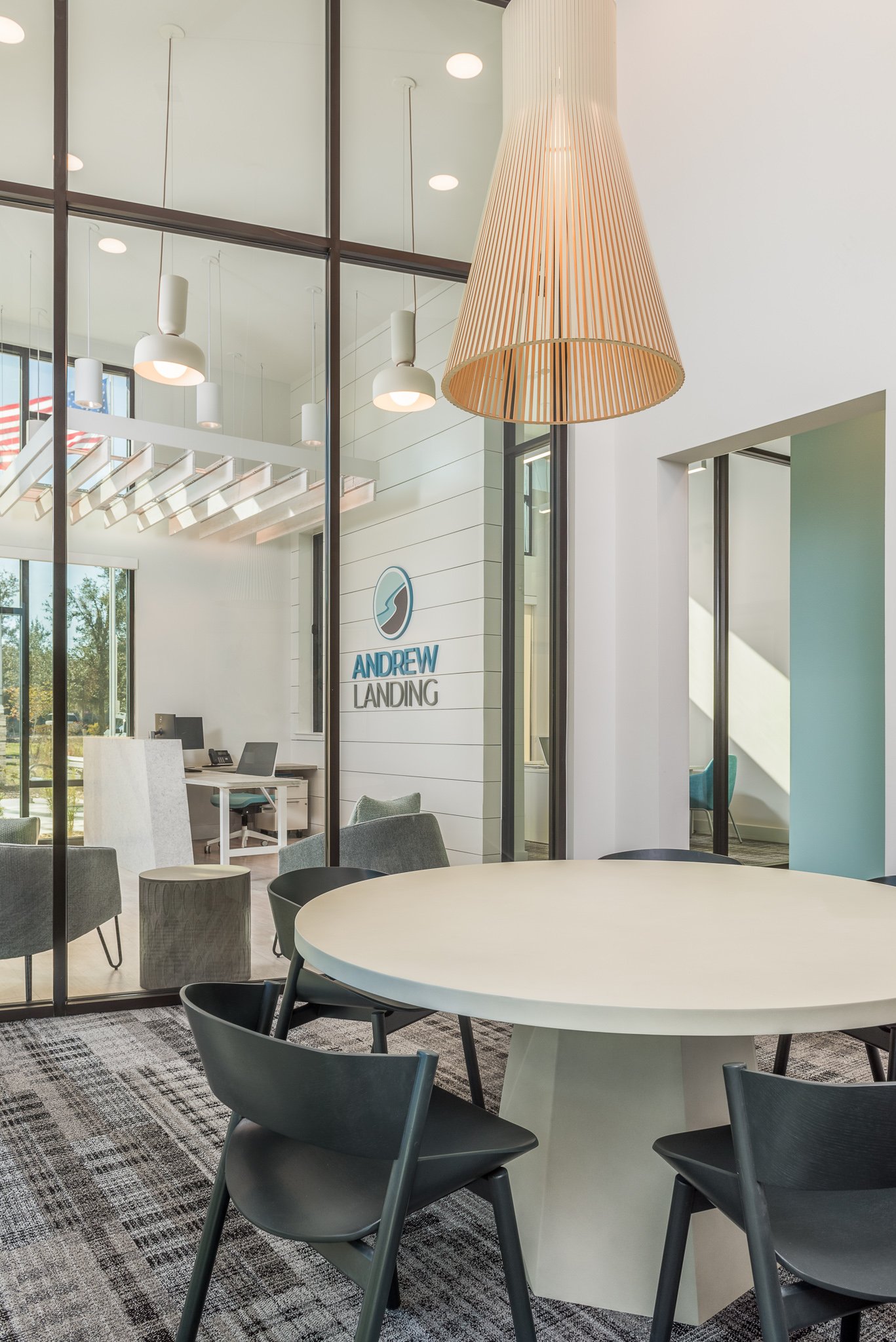 Micamy_Design_Studio_Andrew_Landing_huddle_room_with_large_chandelier_and_table_with_glass_storefront_looking_through_to_the_reception_area.jpg