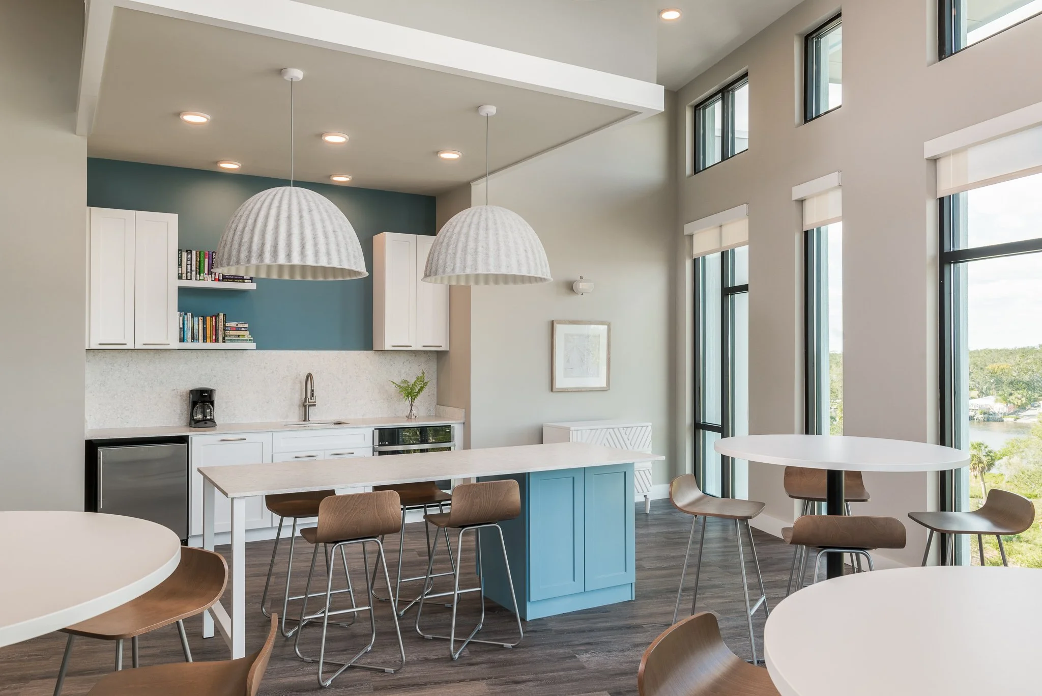 Micamy_Design_Studio_Andrew_Landing_kitchen_with_large_decorative_dome_pendants_and_community_island_backsplash_with_blue_accent_tan_barstools_wide_shot_of_entire_room.jpg