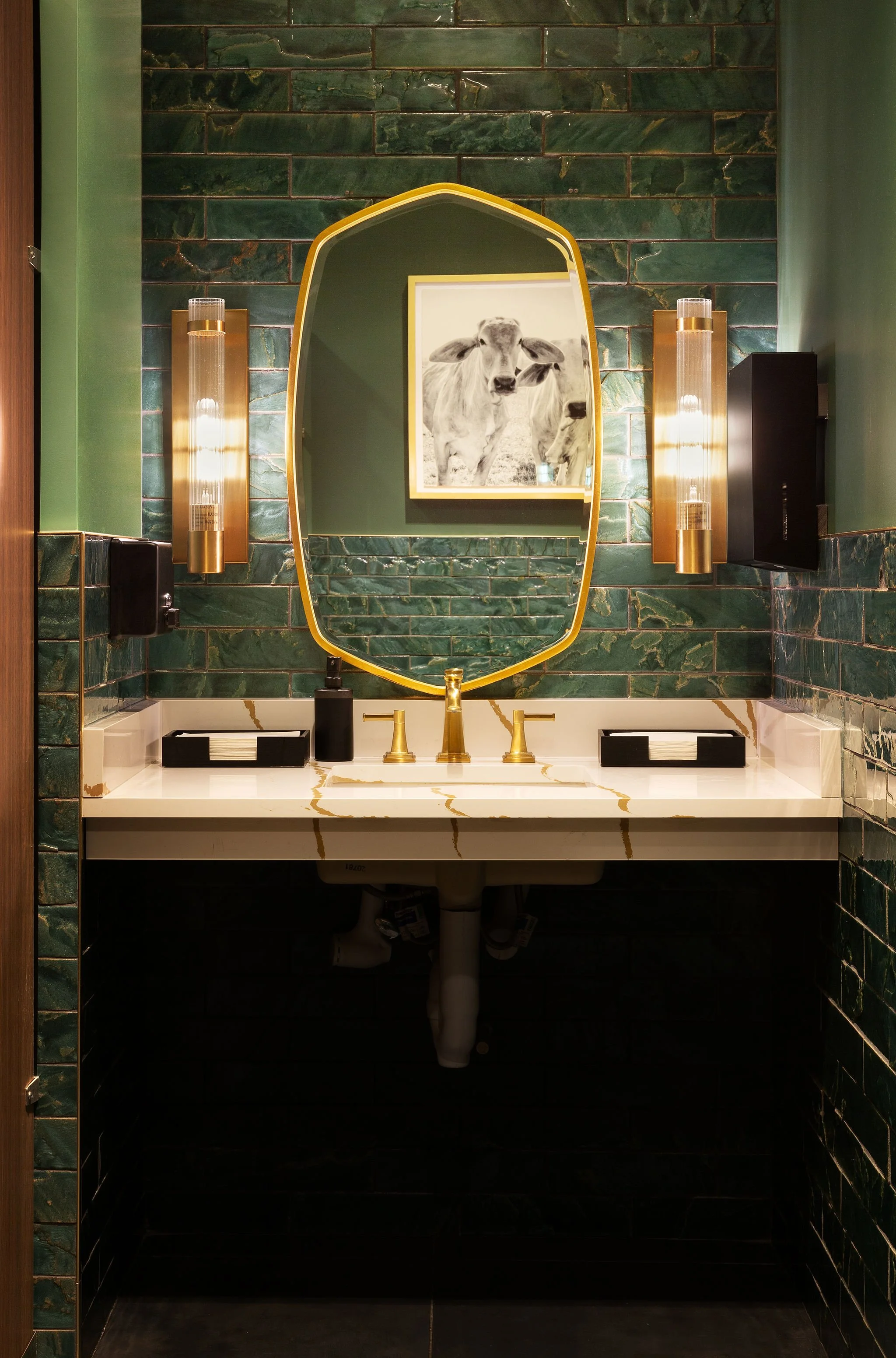 Micamy Design Studio_White Counter_Gold Veining_Gold Faucet_Gold Mirror_Green Glossy Subway Tiles_Gold Sconces_Warm Lighting_Dark Tile Floor.jpg