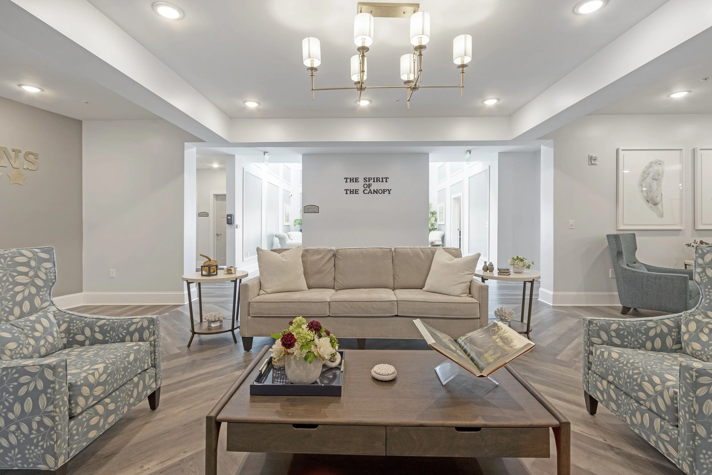 Micamy Design Studio_Canopy at Beacon Woods_Bistro_Beige Couch_Patterned Chairs_Wood Coffee Table_Sign Decor_Chandelier_Wood Look Luxury Vinyl Tile.JPG