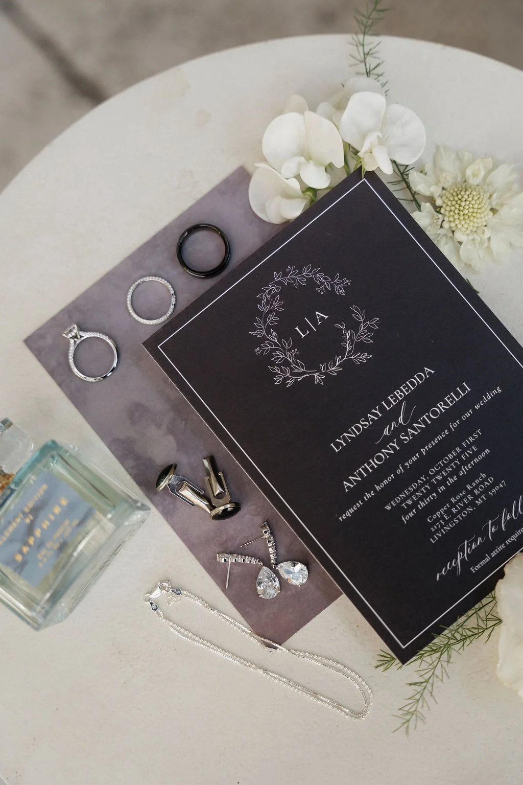bride's invitation sweet with a few flowers, rings and jewelry and a perfume