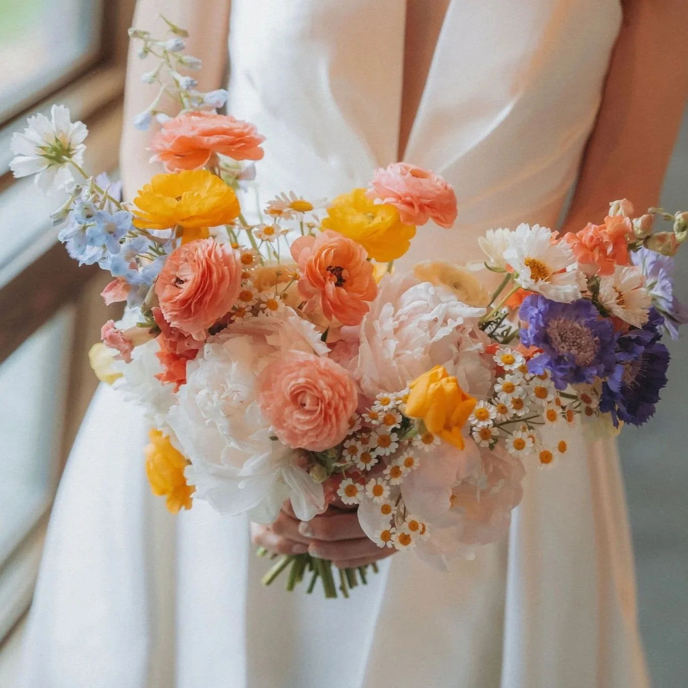 ruffly, peach, light blue and white and yellow bridal bouquet with ranunculus peonies scabiosa and chamomile feverfew