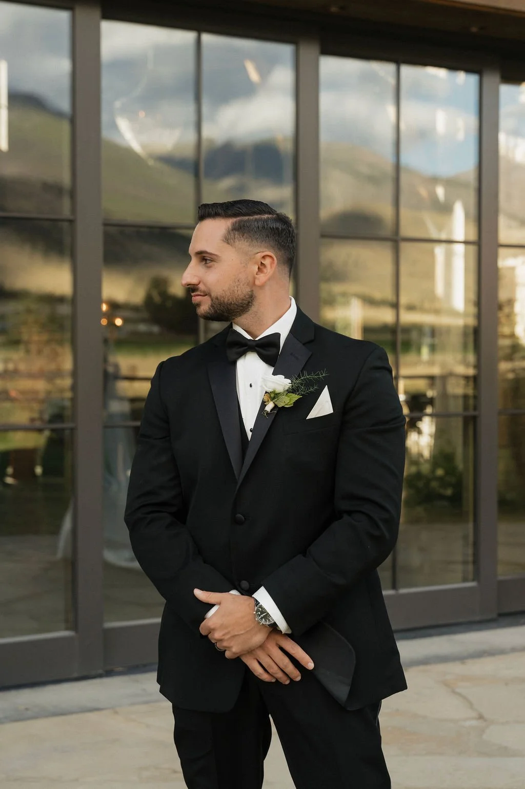 the groom looking to the left with his classy tux and bow tie
