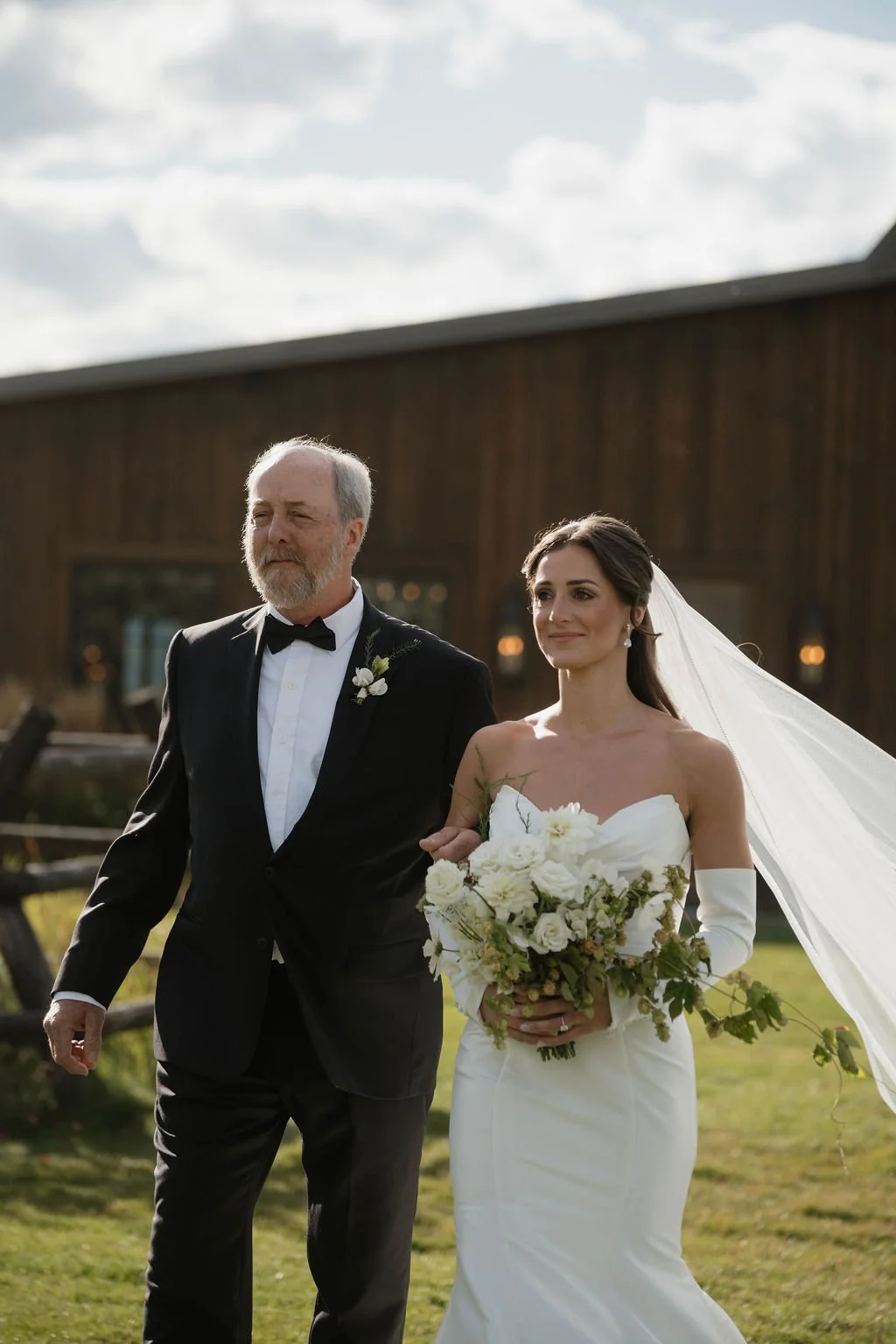 a closer shot of the bride and her father walking down the aisle from the barn at copper rose ranch