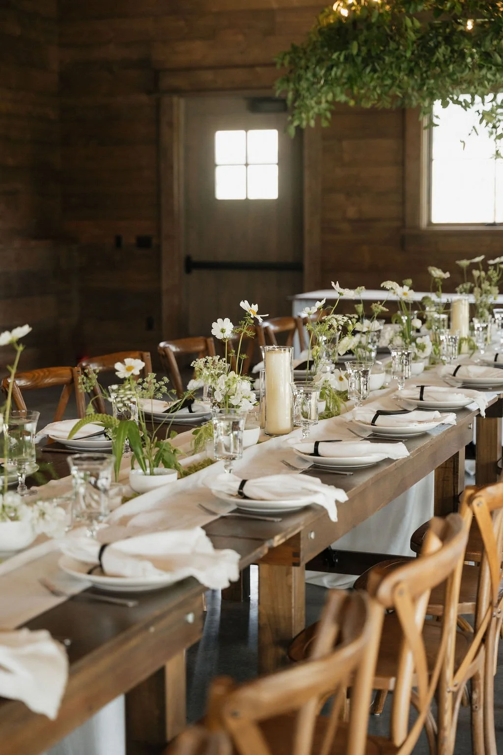 bentwood chair with farmhouse tables white flowers candles and ikebana with greenery on the chandeliers at copper rose ranch