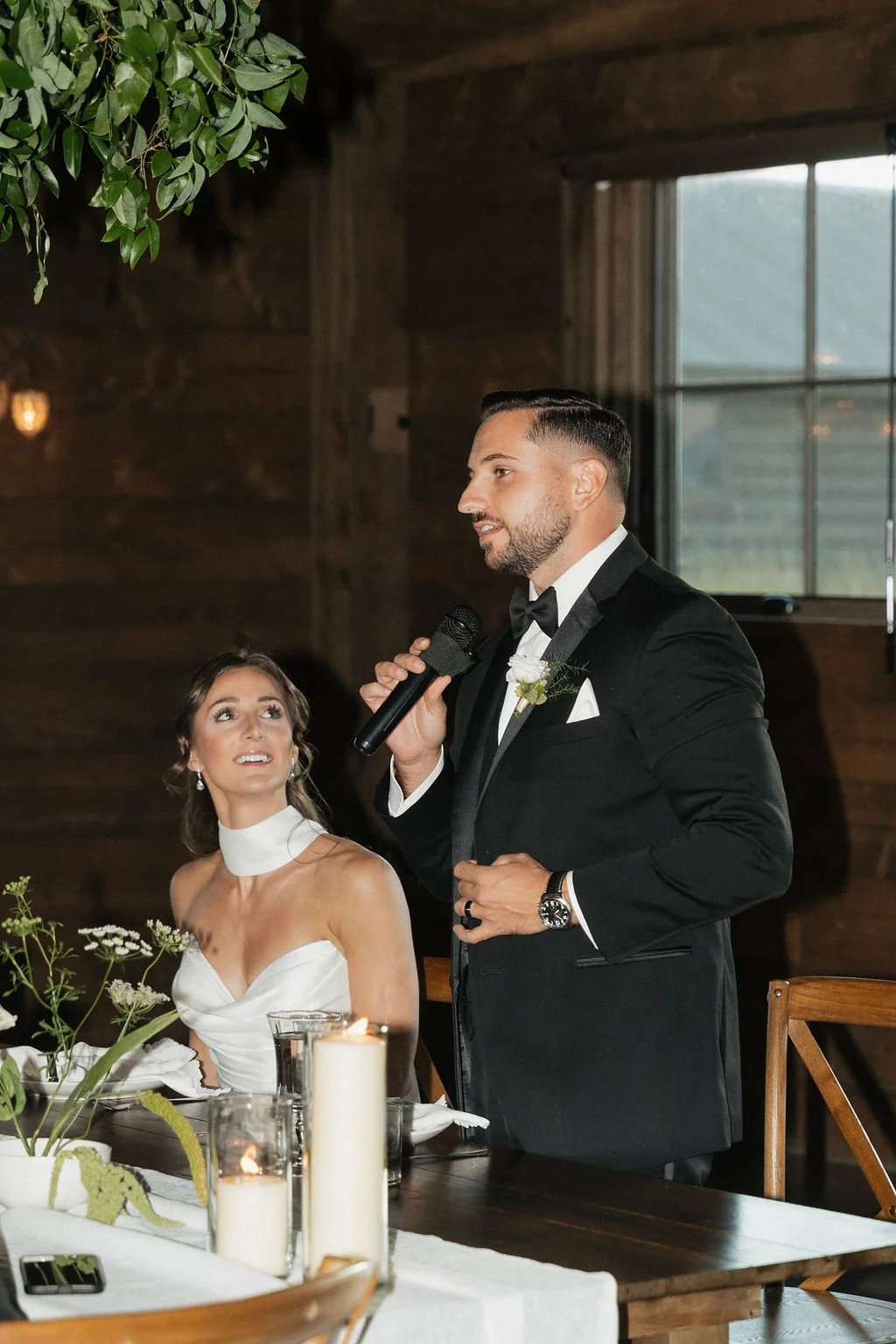the bride sitting and the groom making a speech at the reception in copper rose ranch